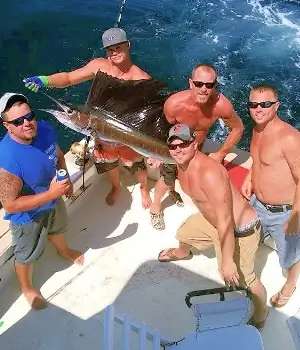 Happy group of anglers show off their marlin for pictures before releasing it on an Outer Banks Charter trip.