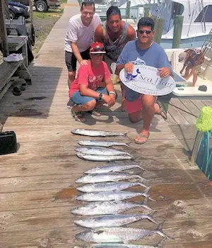 Family posing behind a nice catch of mackerel on a Sea Hag charter trip.